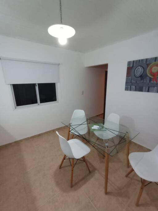 Habitación con mesa de cristal y 2 sillas blancas. en Departamento para dos personas en Monte Hermoso. en Monte Hermoso