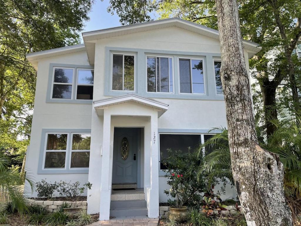 a white house with a blue door and trees at Spacious renovated 4br downtown home w firepit sleeps 8+ in St. Augustine