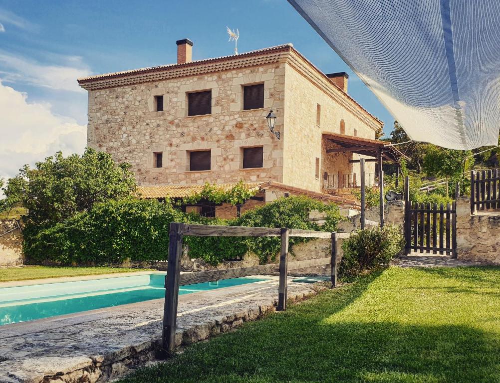 un edificio con piscina frente a una casa en Casa Rural don Rosendo en Olmeda de Cobeta