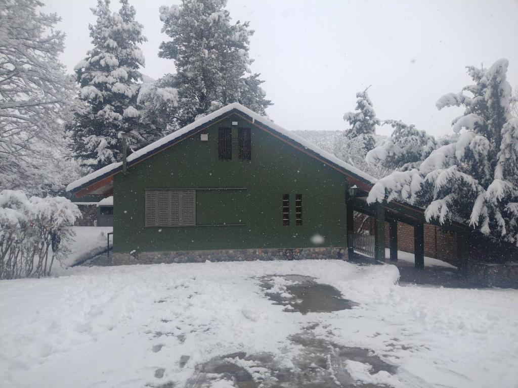 une maison verte dans la neige avec des arbres enneigés dans l'établissement Casa de montaña Manantiales-Nazareth, à Potrerillos