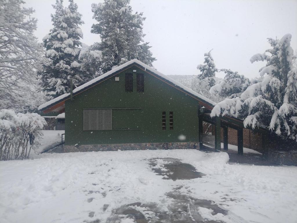 a green house in the snow with snow covered trees at Casa de montaña Manantiales-Nazareth in Potrerillos