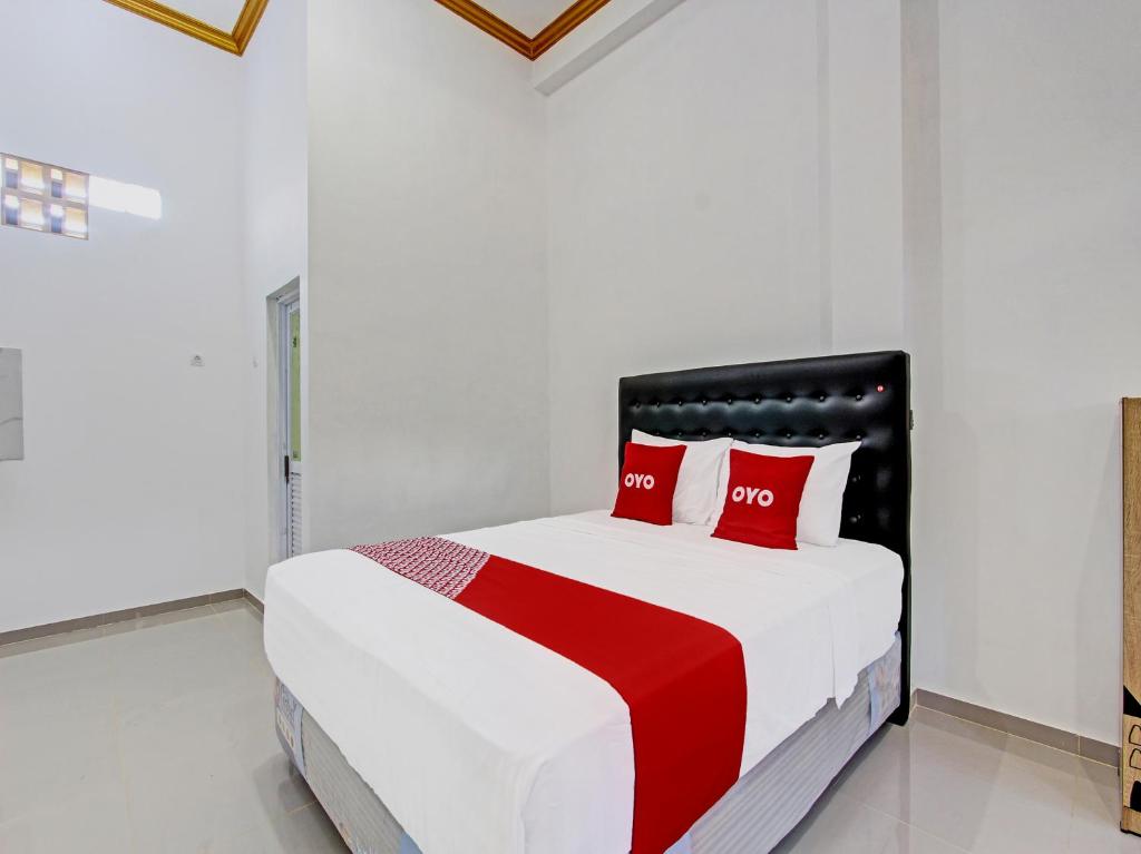 a white bedroom with a bed with red pillows at Super OYO 92101 Elma Guesthouse in Yogyakarta