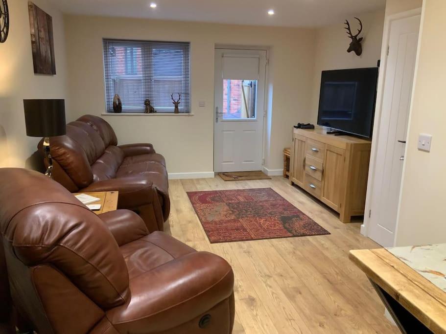 a living room with leather furniture and a flat screen tv at Pet Friendly Cottage Ashbourne with Parking in Ashbourne