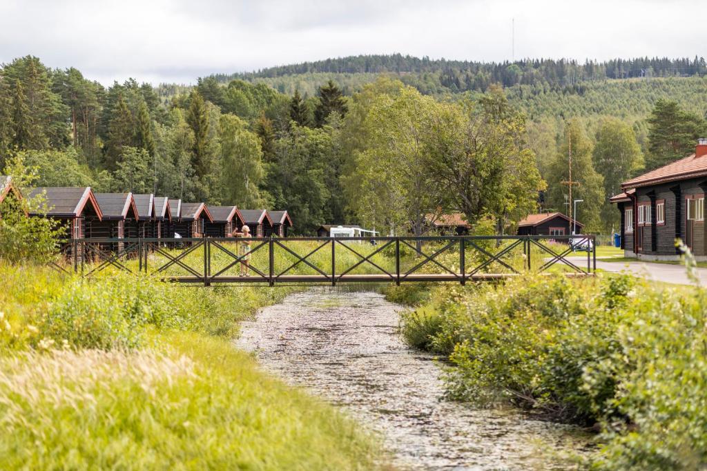 eine Brücke über einen Fluss mit Häusern und Bäumen in der Unterkunft First Camp Enåbadet - Rättvik in Rättvik
