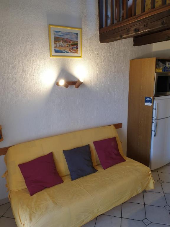 a yellow couch in a room with two pillows on it at Studio Mezzanine vue port et mer in La Londe-les-Maures