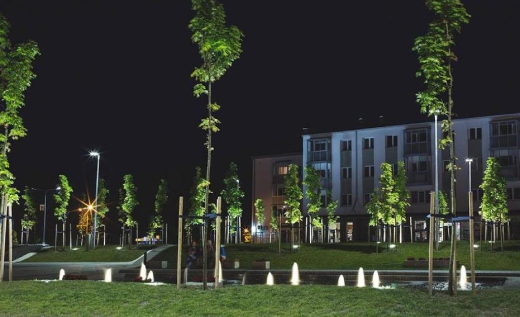 a building with trees in front of it at night at nr 30 with view balcony in Ramučiai