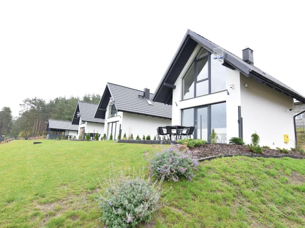 a white house with a grassy yard at Modern holiday homes directly on the lake in Kiedrowice in Kiedrowice