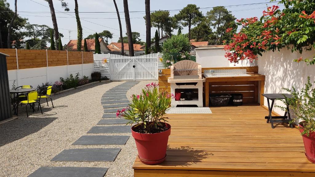 une terrasse en bois avec des plantes en pot et une table dans l'établissement chez fifi, à Saint-Brévin-les-Pins