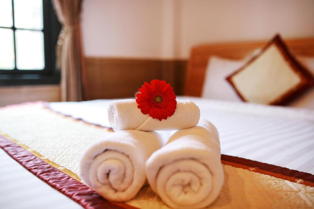 a pile of towels with a red flower on a bed at KB VILLA in Da Lat