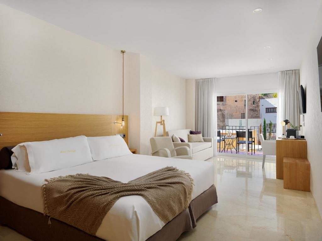 a bedroom with a large bed and a living room at Hotel Saratoga in Palma de Mallorca