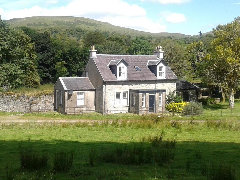 an old stone house in a field of grass at Garden Cottage in Strachur