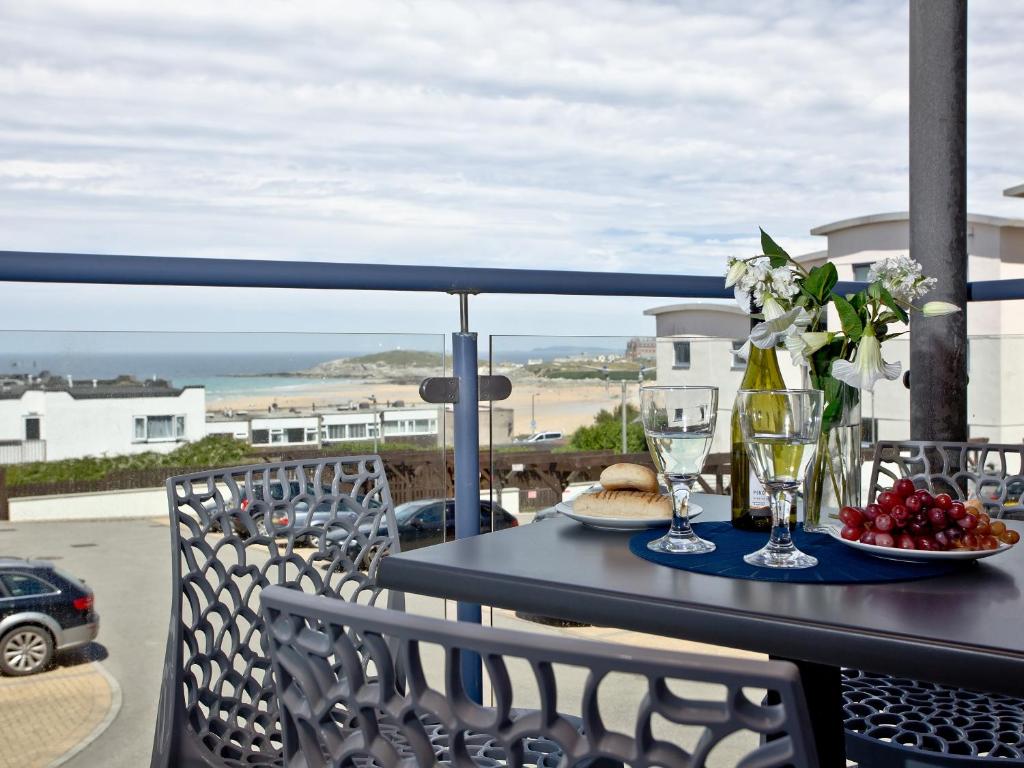 een tafel met wijnglazen en bloemen op een balkon bij Fistral Escape in Crantock
