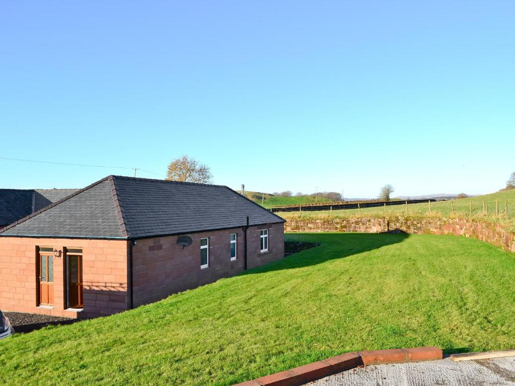 a house on a hill with a grassy yard at Liftingstane Cottage in Closeburn