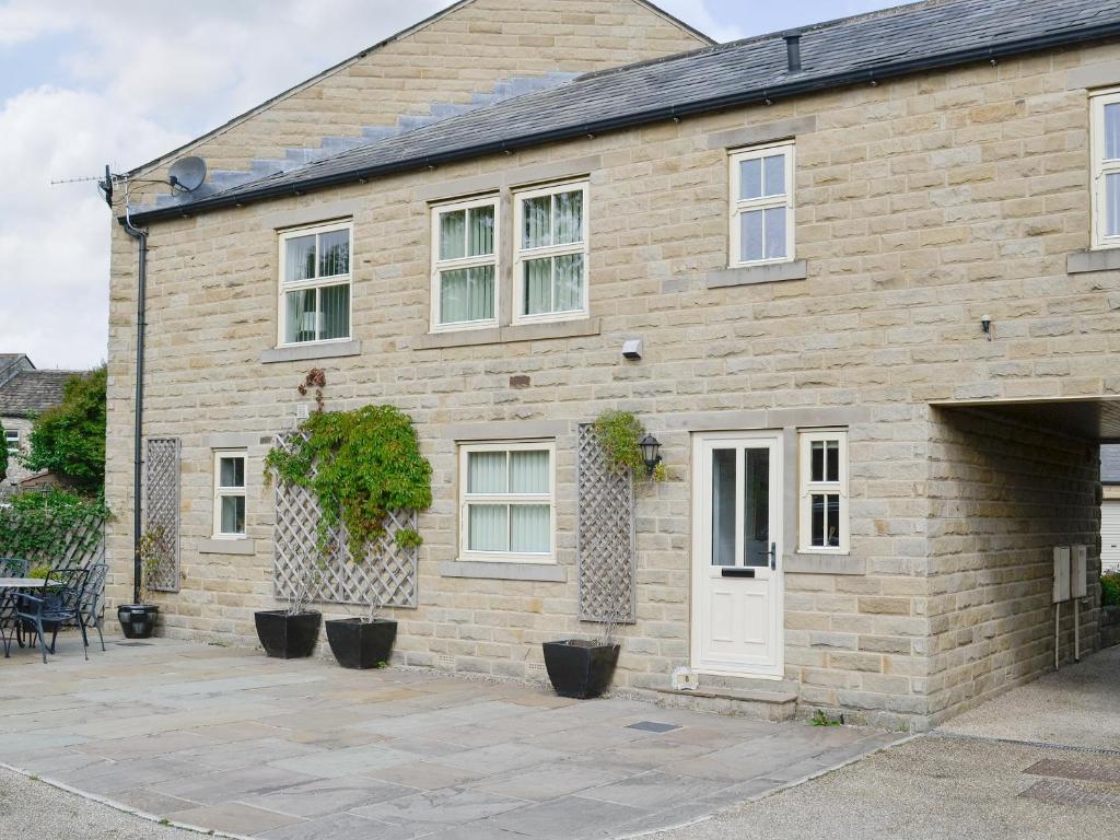 a brick house with a white door and a patio at Mickle Hill Mews in Gargrave