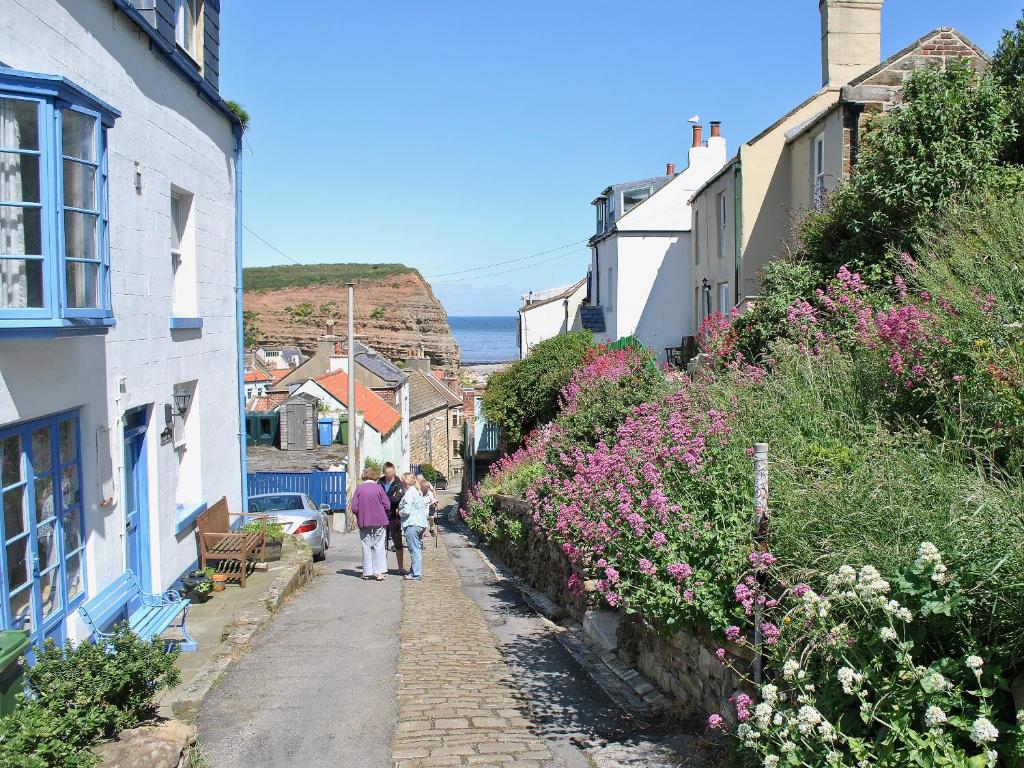 a group of people walking down a street with flowers at Felicity Cottage in Staithes