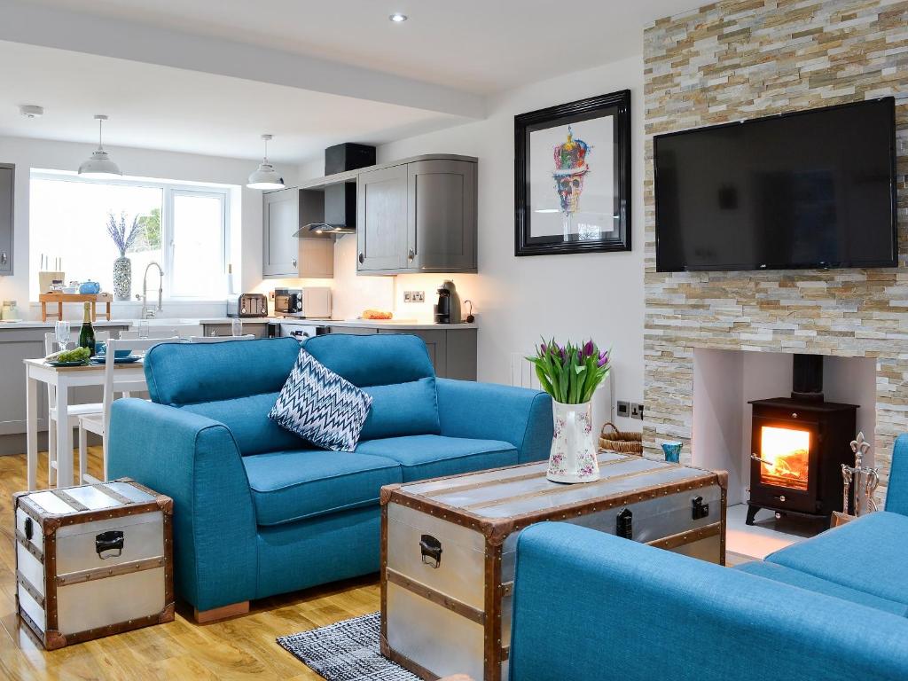 a living room with blue couches and a fireplace at Key To The Esk in Longtown