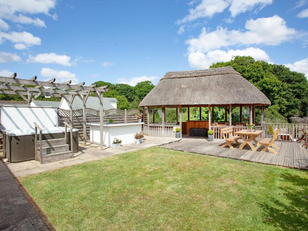 a garden with a gazebo with a table and benches at Sundance in Cheriton Bishop