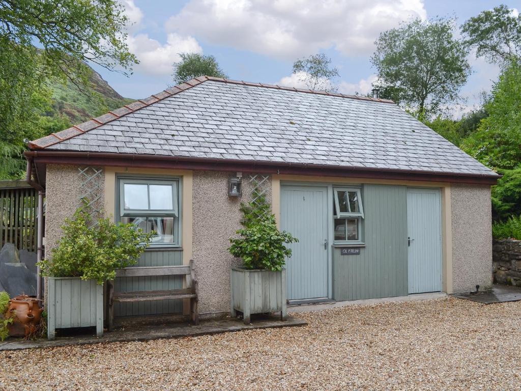 a small house with a garage and two plants at Cil Y Felin in Beddgelert