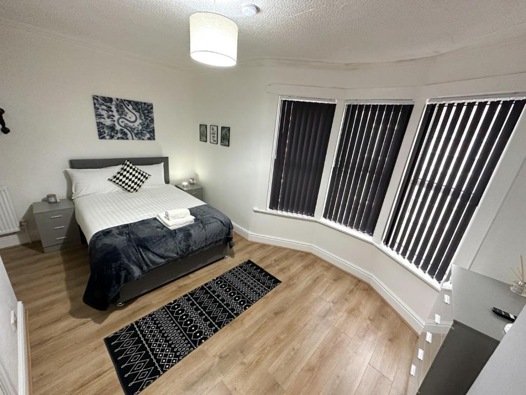 a bedroom with a bed and two large windows at Wenlock Liverpool in Liverpool