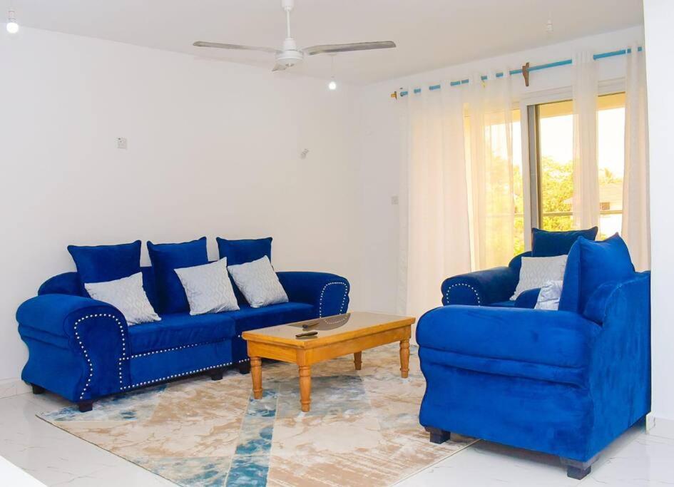 ein Wohnzimmer mit 2 blauen Sofas und einem Couchtisch in der Unterkunft 2 B/room Nyali City Mall W/Pool in Mombasa