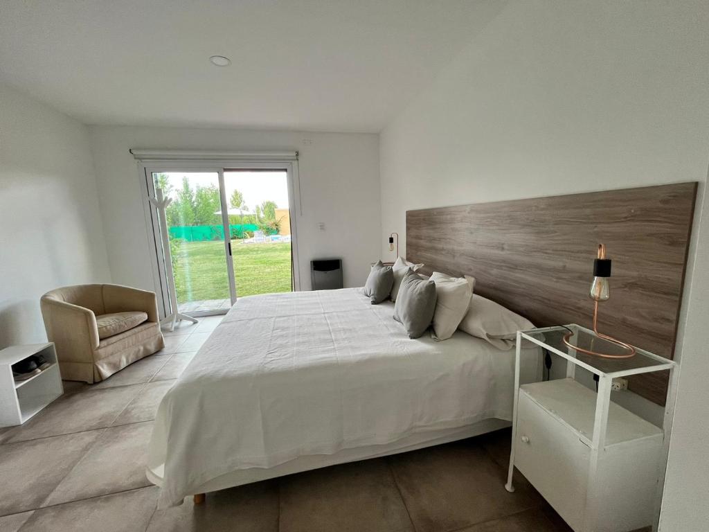 ein weißes Schlafzimmer mit einem großen Bett und einem Stuhl in der Unterkunft Pergolas Guest House - Pileta, Vinos y Montaña in Vista Flores