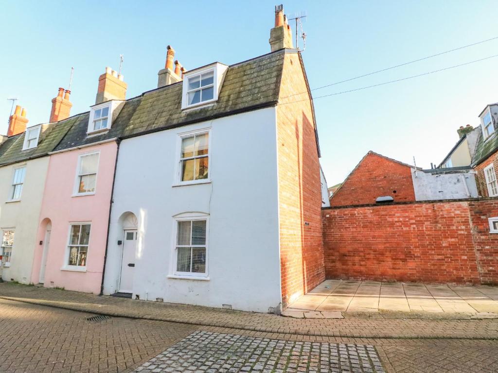 a white house with a red brick wall at Lobster Cottage in Weymouth