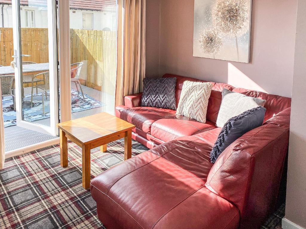 een woonkamer met een rode leren bank en een tafel bij Jasmins Retreat in Cleveleys