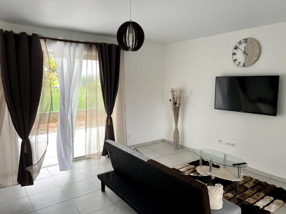 ein Wohnzimmer mit einem Sofa und einer Uhr an der Wand in der Unterkunft Maison T3 neuve fonctionnelle in Matoury
