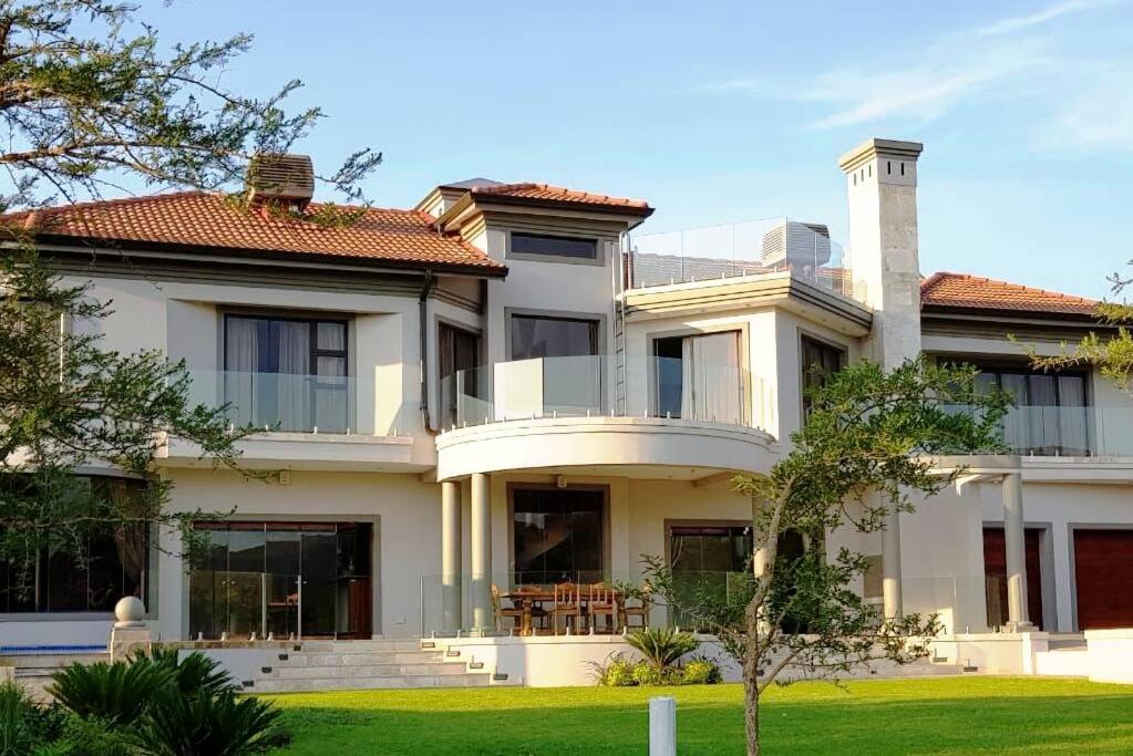 a large white house with a green yard at Spacious Golf & Wildlife Estate in Hartbeespoort 10 sleeper in Hartbeespoort