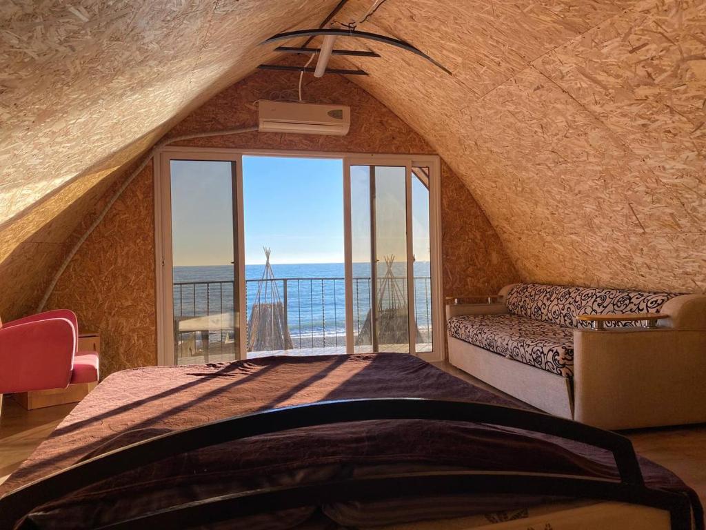 una camera da letto con una grande finestra con vista sull'oceano di Дом с видом на море на Белом пляже a Novy Afon