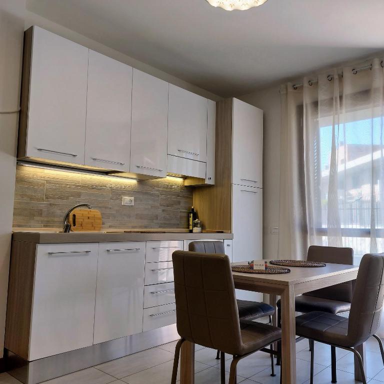 una cucina con armadi bianchi, tavolo e sedie di Monolocale in Via Flaminia - Alloggio Turistico a Roma