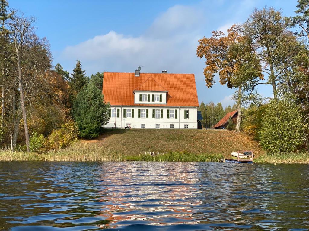 a house on a hill next to a body of water at Leśniczówka Szeroki Bór in Szeroki Bór