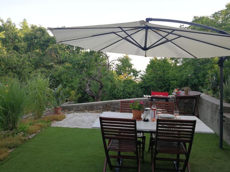 einen Tisch und Stühle unter einem Sonnenschirm in einem Garten in der Unterkunft CASA MINI 5 in Pécs