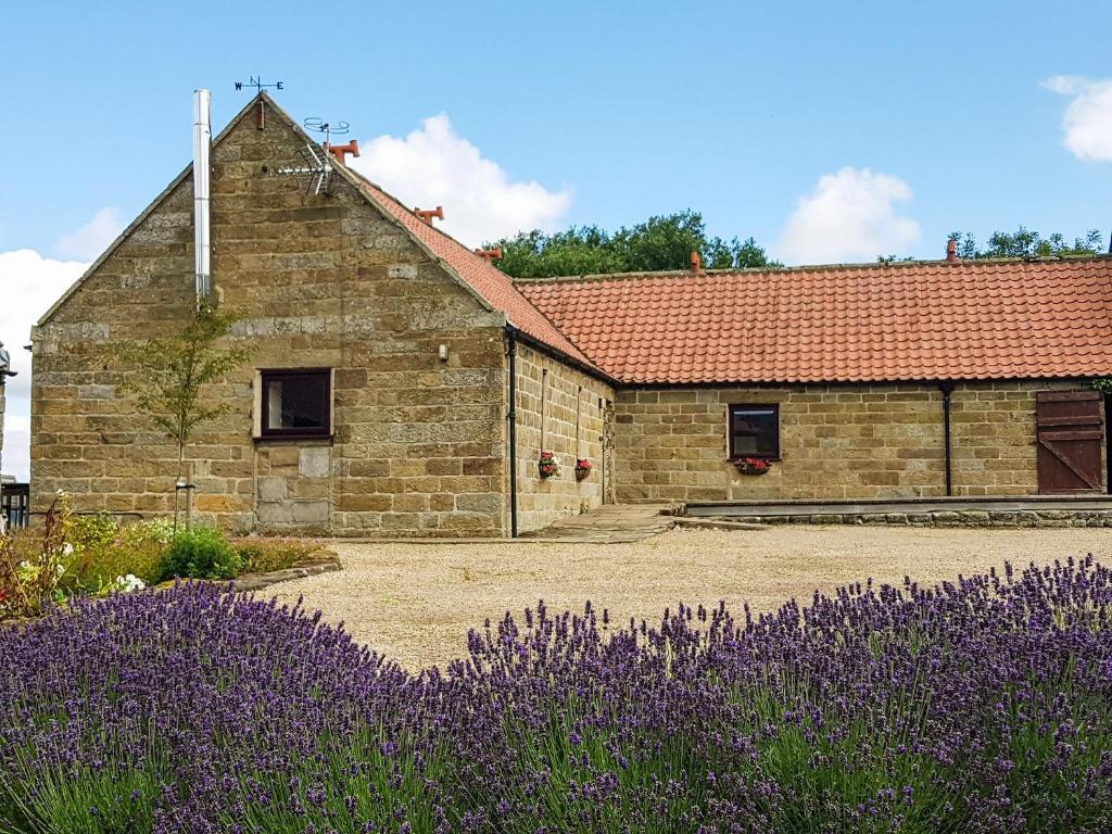 a stone building with purple flowers in front of it at The Byre in Westerdale