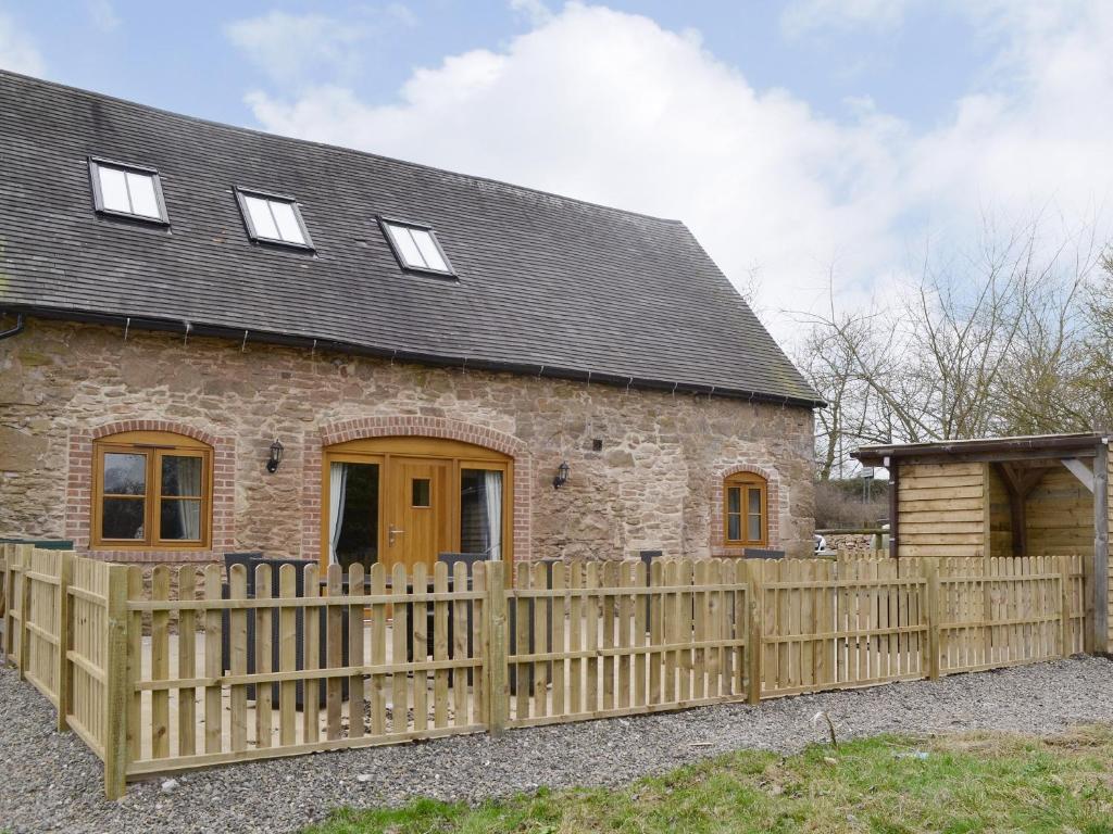 a stone house with a wooden fence in front of it at No, 1 Ash Cottage in Quatt