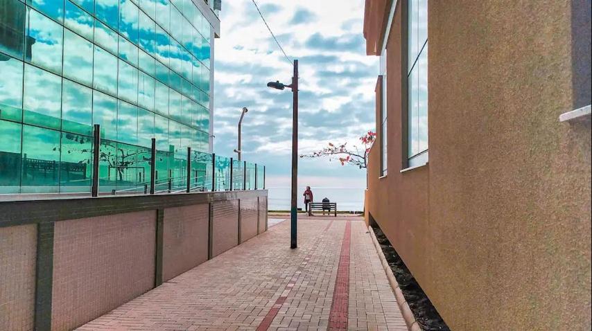 a sidewalk next to a building with a person sitting on a bench at Apto Meia Praia/Itapema in Itapema