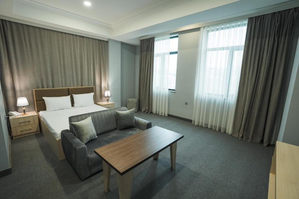 um quarto de hotel com uma cama, um sofá e uma mesa em Ogguesto Hotel em Baku