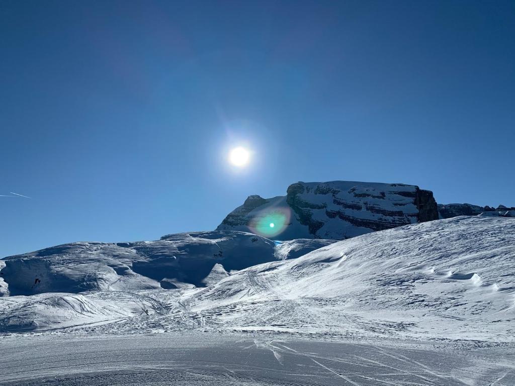 a snow covered mountain with the sun in the sky at Des Alpes C Flat 11 in Madonna di Campiglio