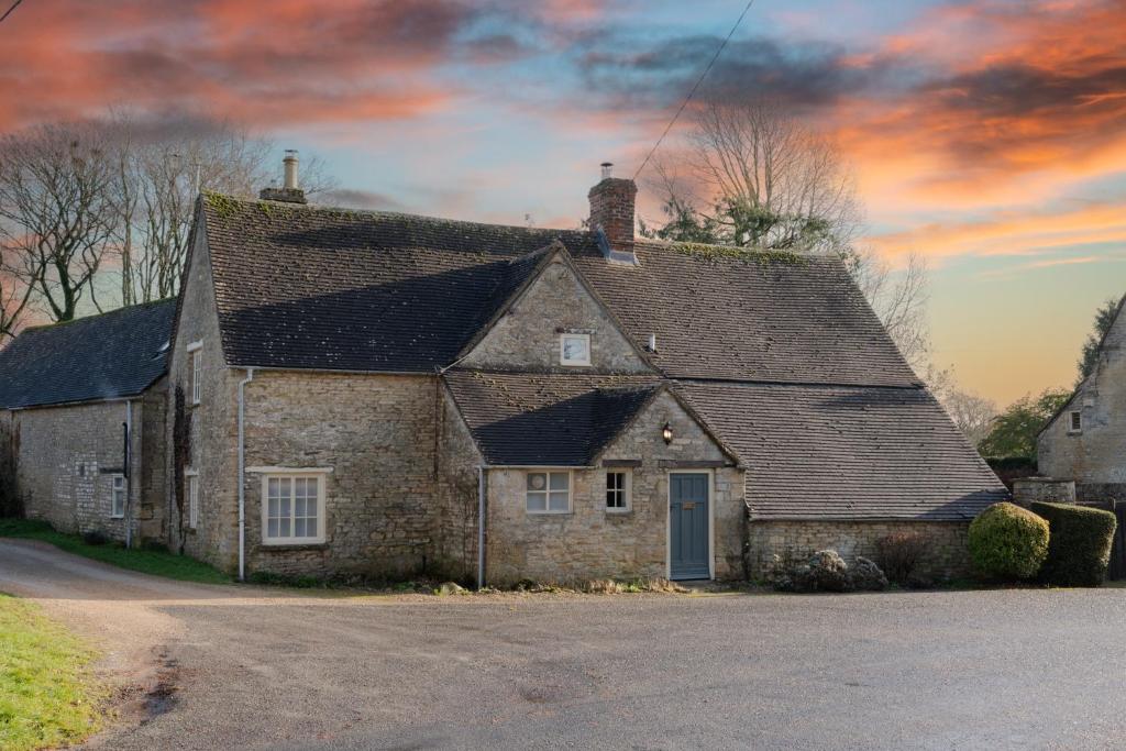 una vieja casa de piedra con techo en una calle en Woodmancote Manor Cottage en Cirencester