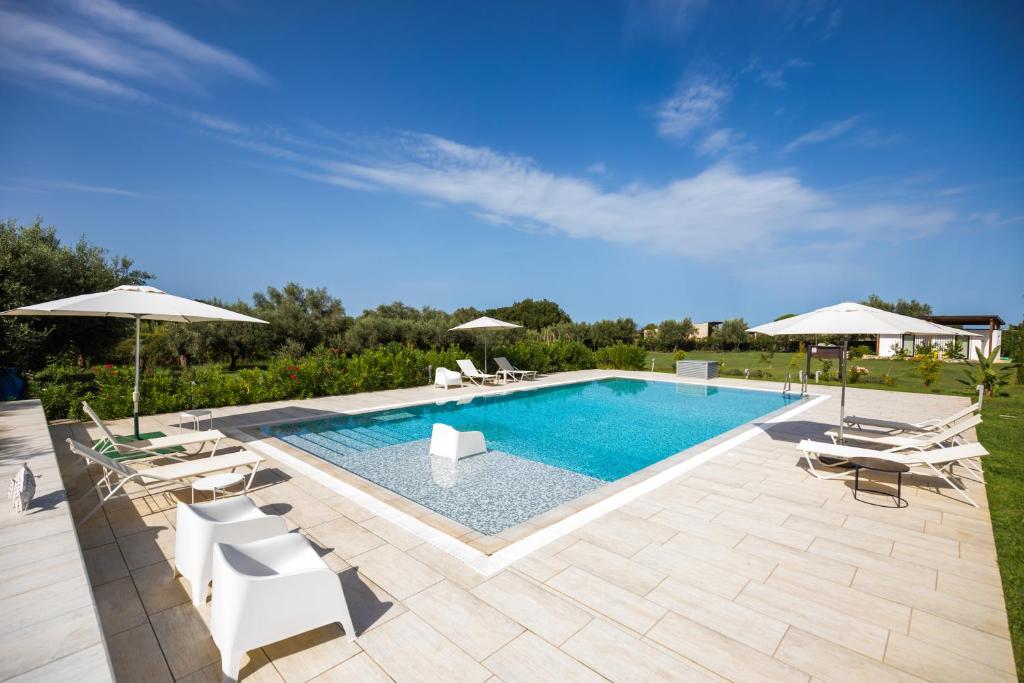 una piscina con sillas y sombrillas blancas en Gallo Fino, en Ricadi