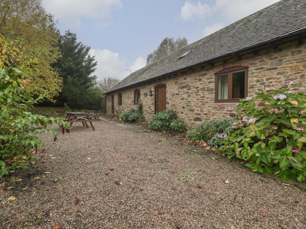 un edificio in pietra con una panchina accanto di Cinder Cottage a Worcester