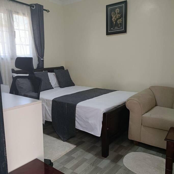 a bedroom with a bed and a couch and a chair at Sharz place in Nairobi