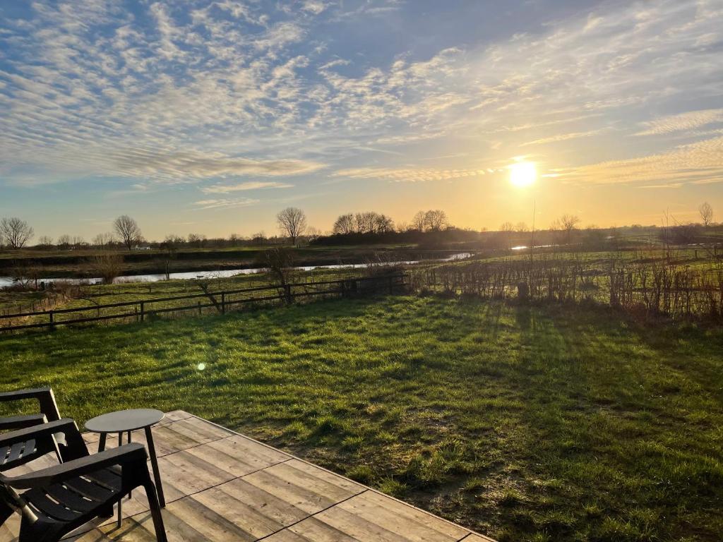 a sunset over a field with a table and chairs at Containerwoning op schitterende locatie in Milsbeek