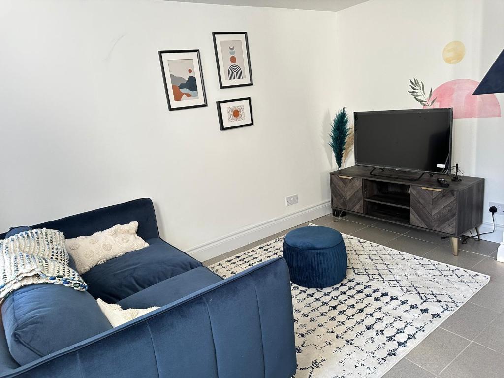 ein Wohnzimmer mit einem blauen Sofa und einem TV in der Unterkunft Cosy One Bedroom Apartment in Trowbridge