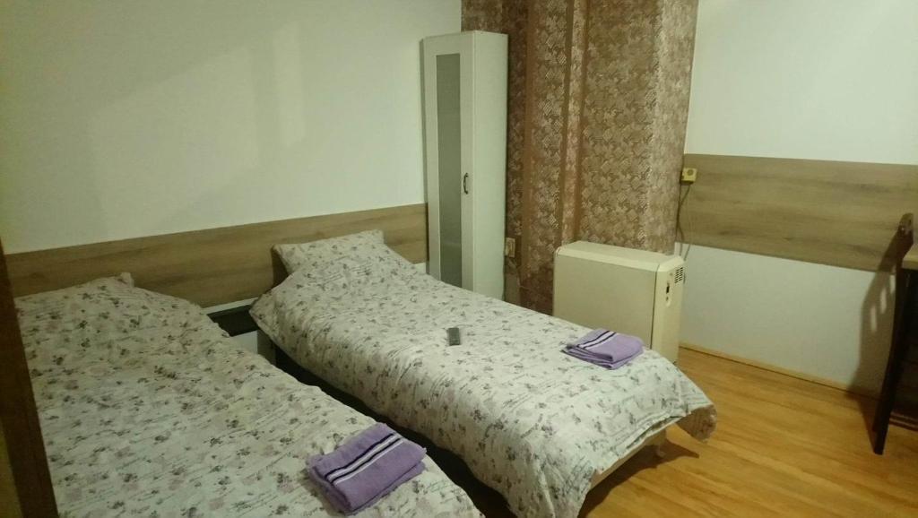 two beds in a bedroom with purple towels on them at SOBA ROYAL 5 in Šabac