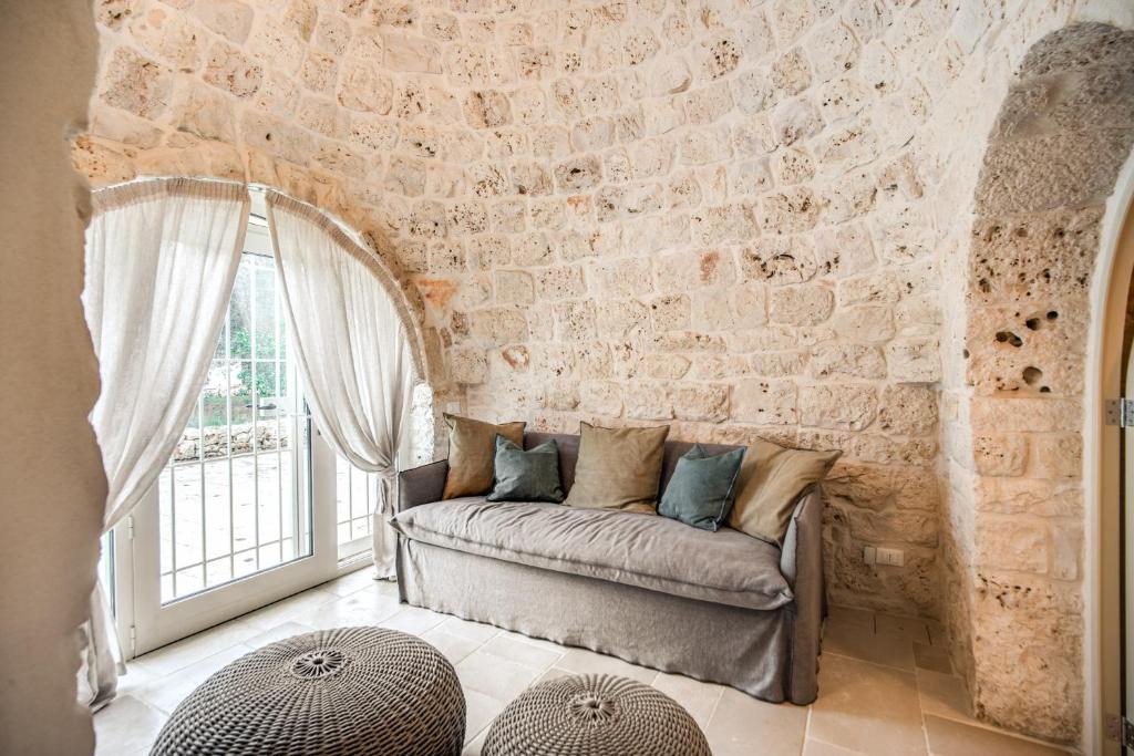 a living room with a couch and a stone wall at Trullo Rosa del Sud-Benessere SPA in Ceglie Messapica