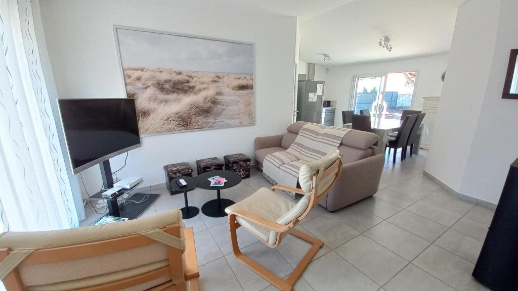 salon z kanapą i telewizorem z płaskim ekranem w obiekcie LES SILENES - Maison 3 chambres proche plage w mieście Saint-Jean-de-Monts