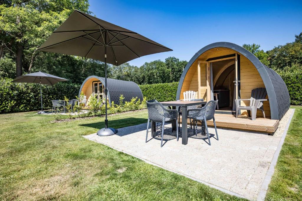 een ronde tent met een tafel en stoelen en een paraplu bij Luxe woodlodge in een prachtige en bosrijke omgeving in Bornerbroek