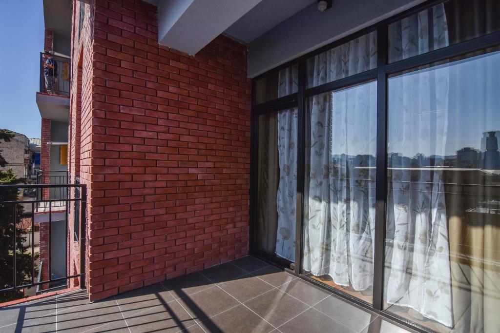 Elle comprend un balcon avec un mur en briques et de grandes fenêtres. dans l'établissement Ninoshvili's Painter's Home, à Tbilissi