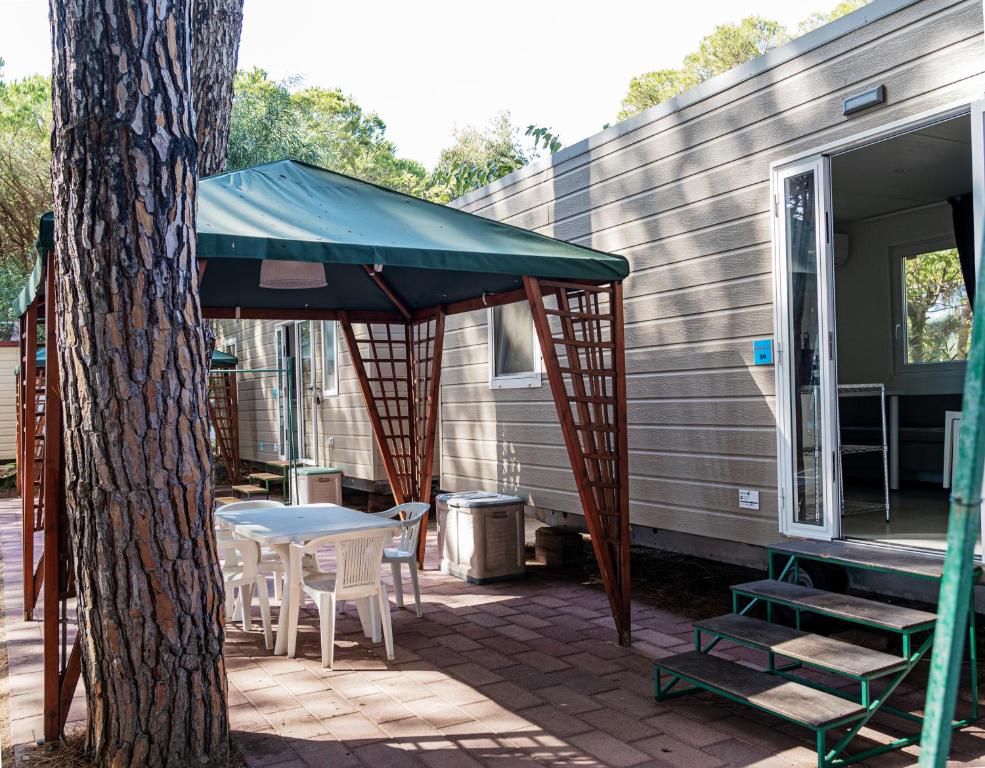 - une terrasse avec une table et un parasol à côté d'une maison dans l'établissement Camping&Village Le Cernie, à Lotzorai